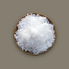 Wooden bowl filled with white granulated sodium hydroxide on a brown background