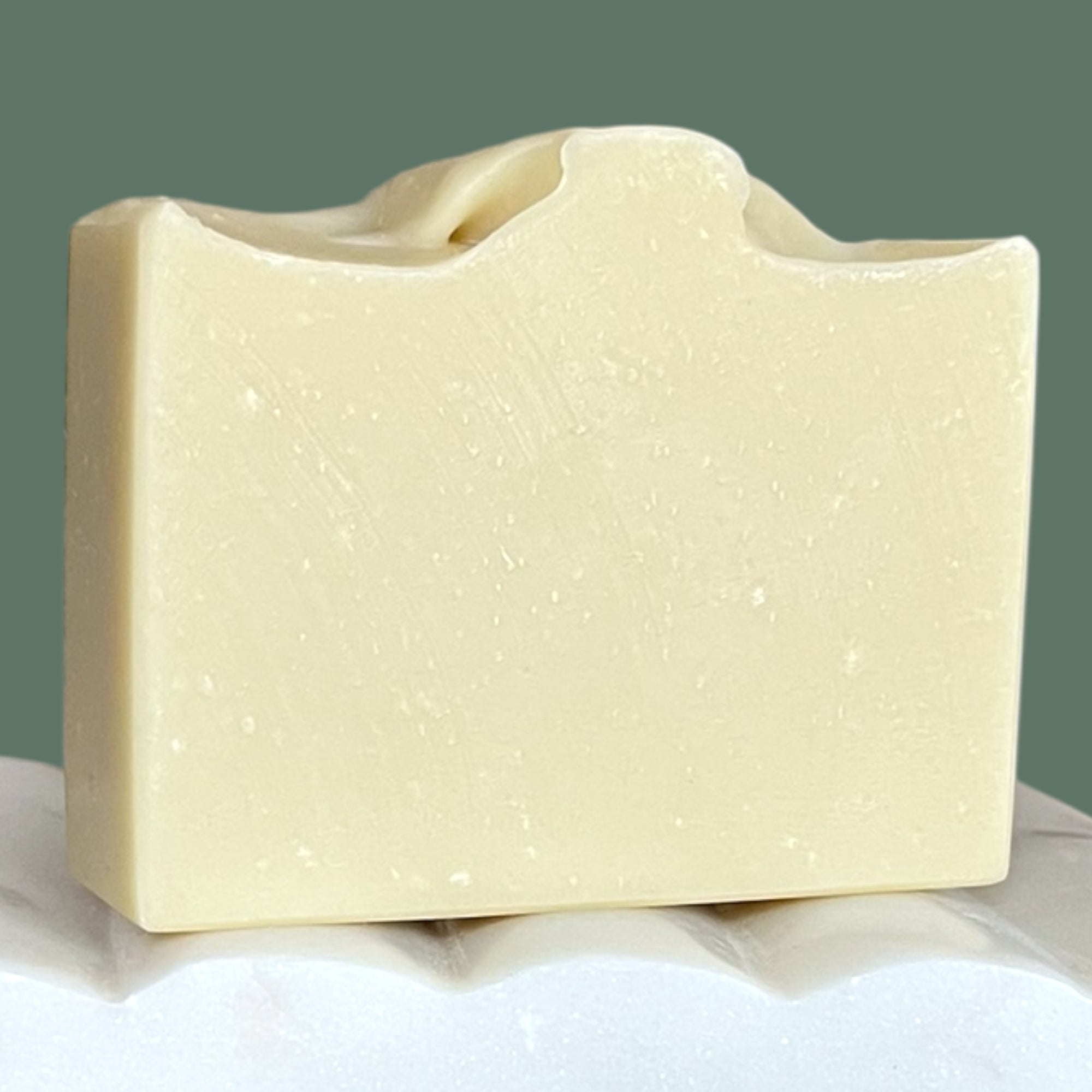 Pastel green soap bar with lightly textured surface with a green background