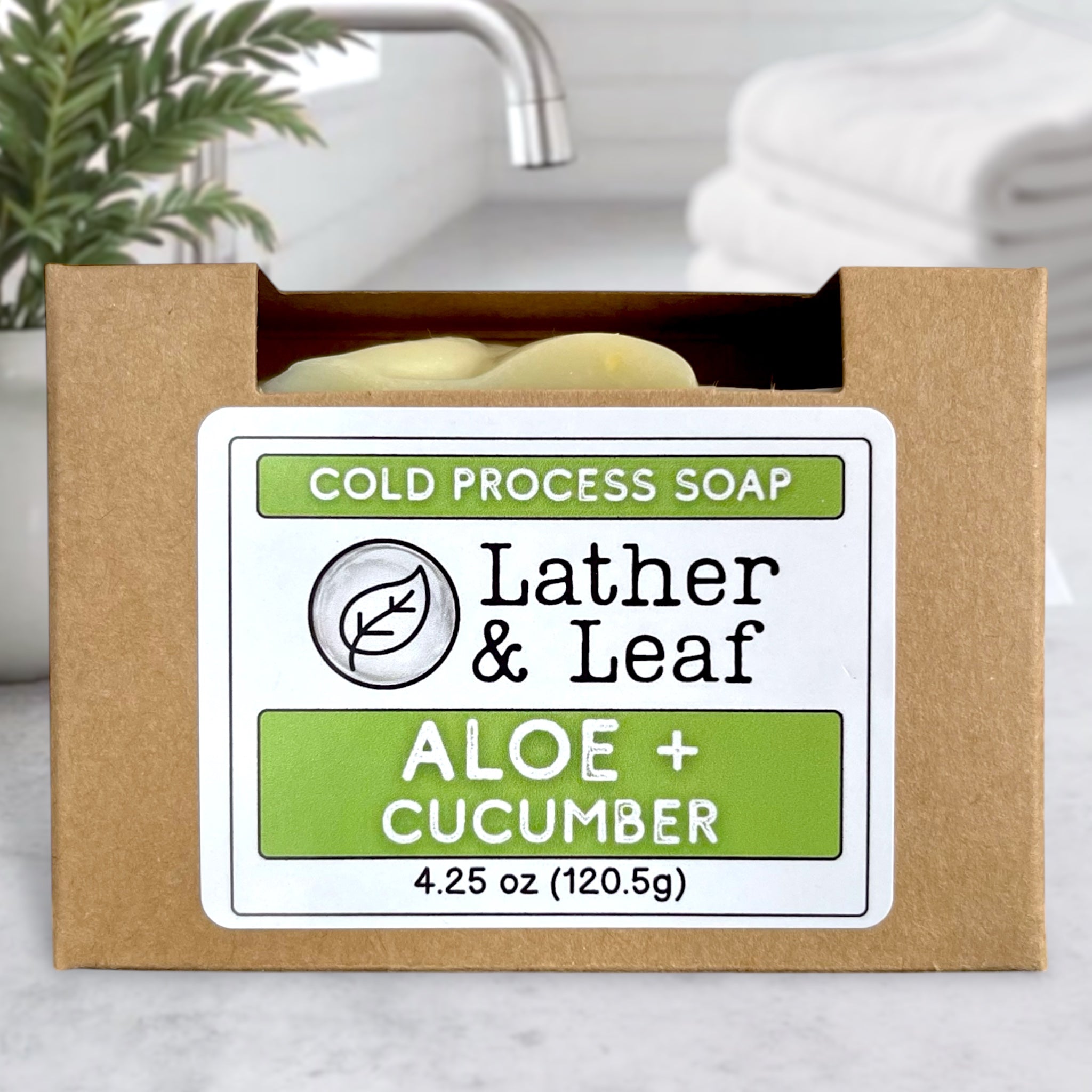Cold process soap bar labeled 'Lather & Leaf Aloe + Cucumber' in a brown box.