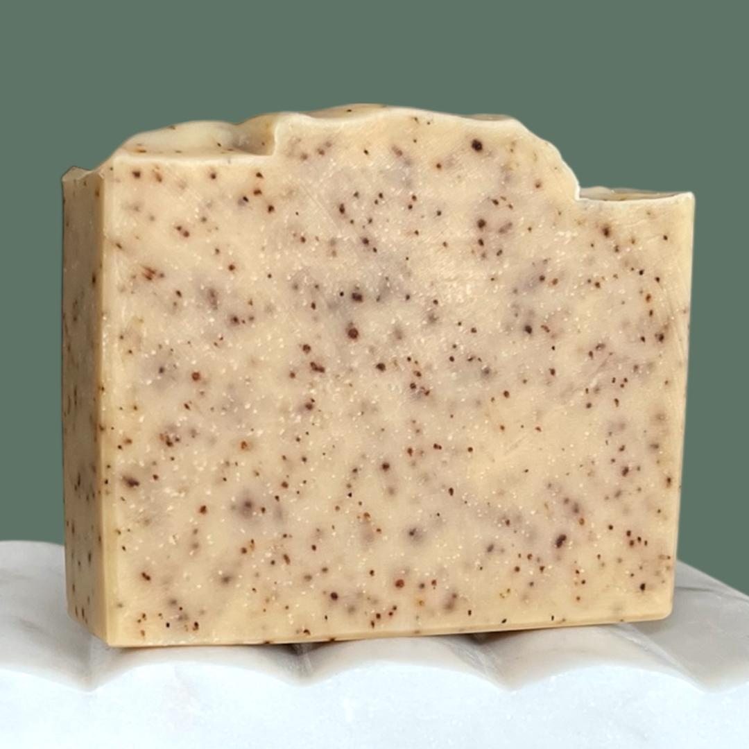 Bar of soap with specks on a white surface and green background