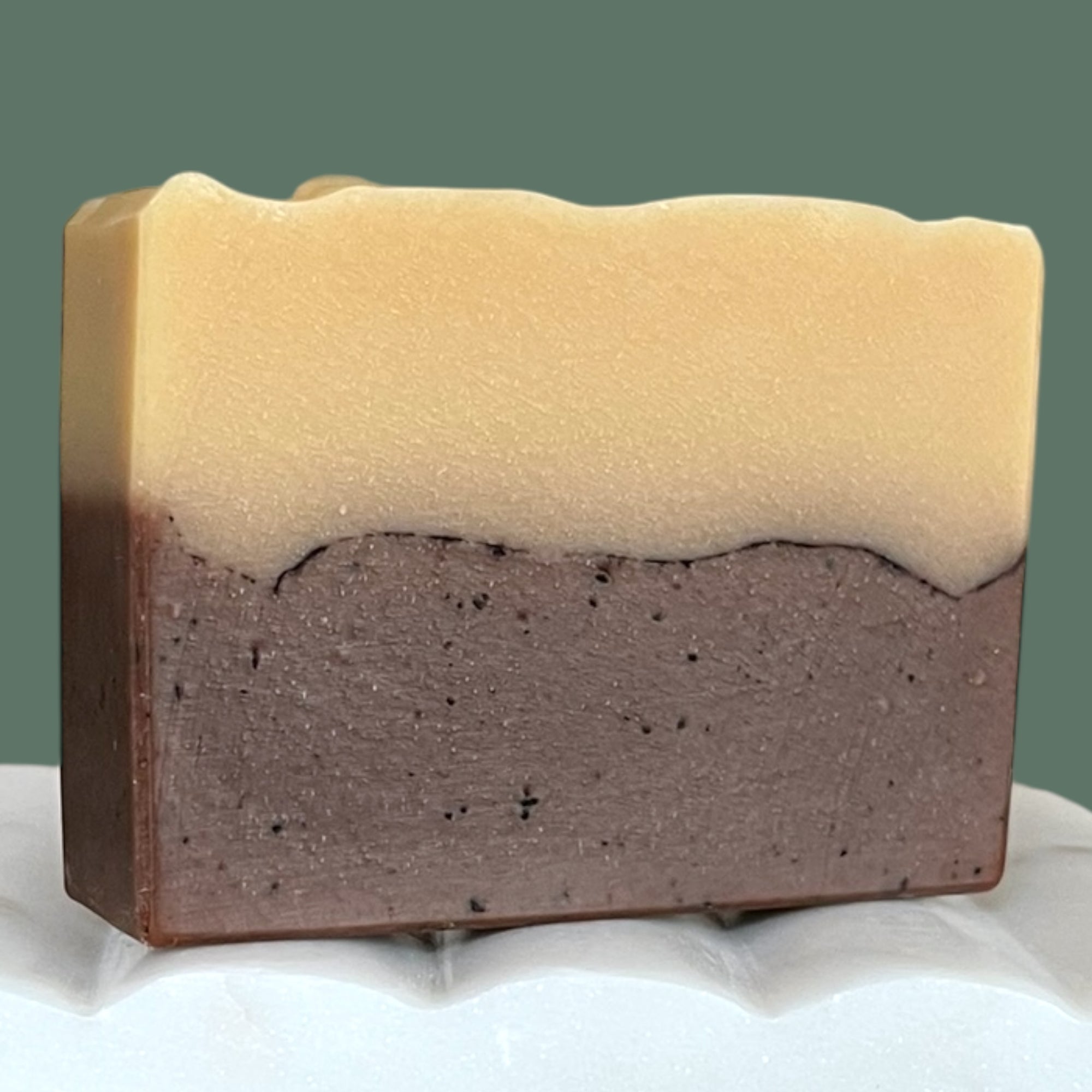Two layered soap bar with beige top and brown bottom on a white surface.