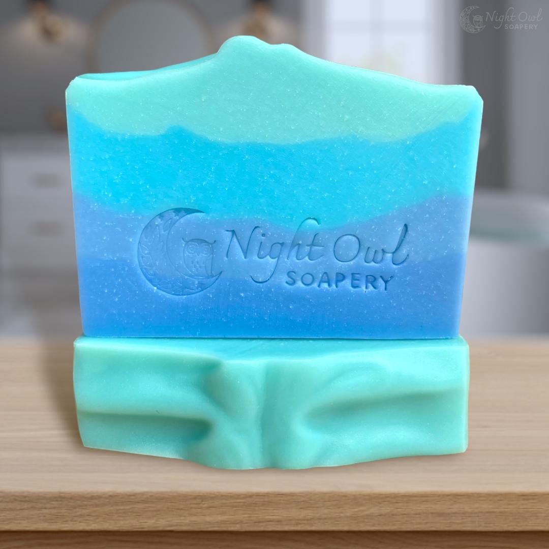Blue and teal soap bar with 'Night Owl Soapery' branding on a wooden surface.