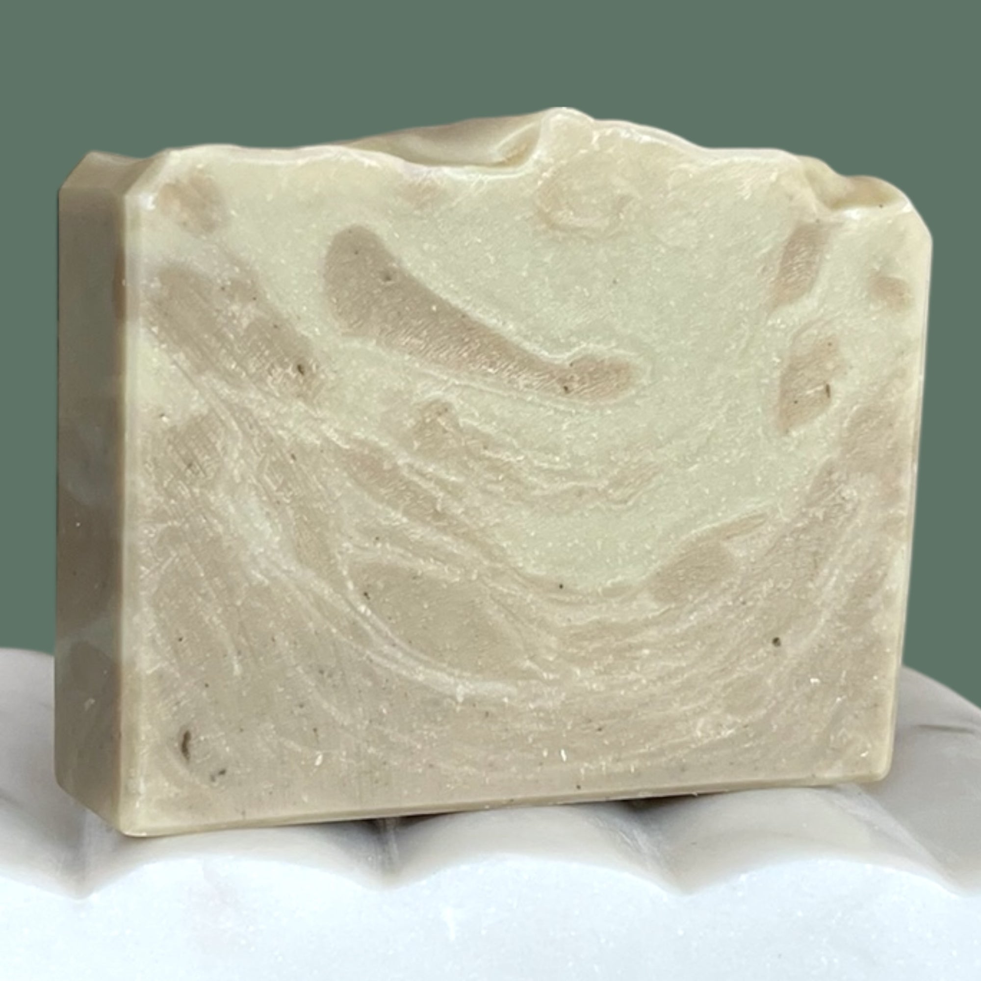 Bar of soap with a marbled beige and green-blue pattern on a white surface