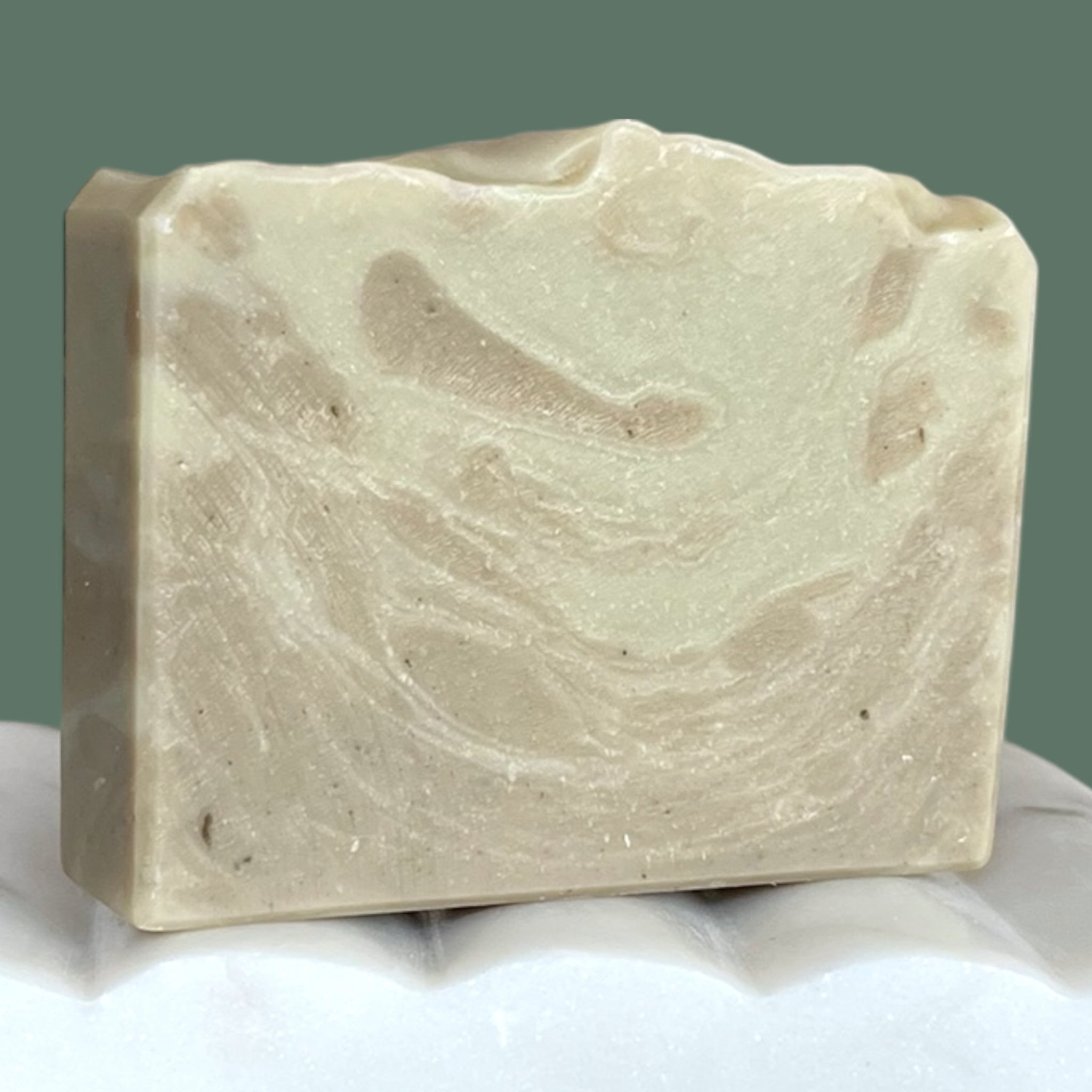 Bar of soap with a marbled beige and green-blue pattern on a white surface