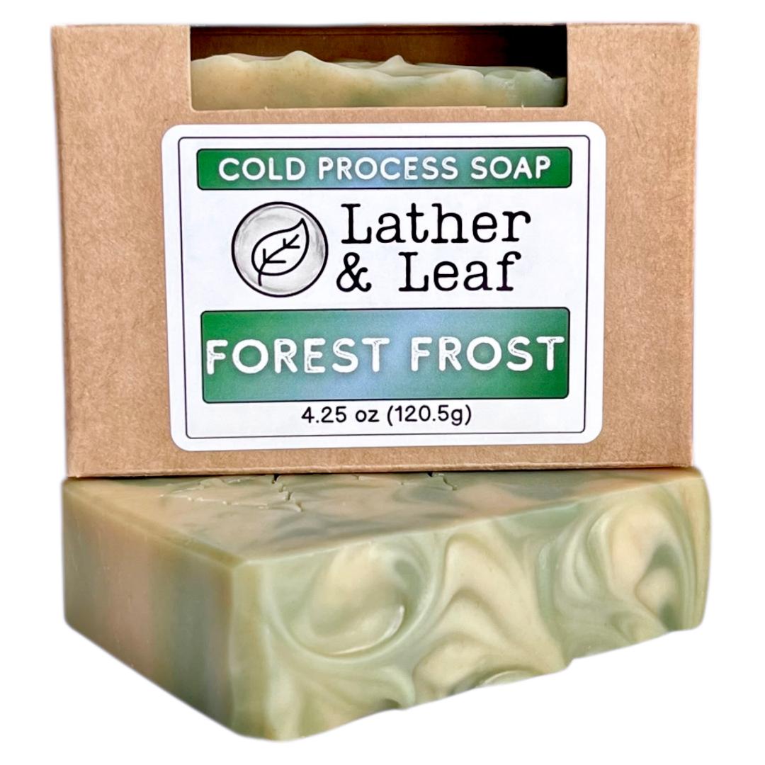 Cold process soap bar with 'Lather & Leaf' on a kraft colored box packaging on a white background