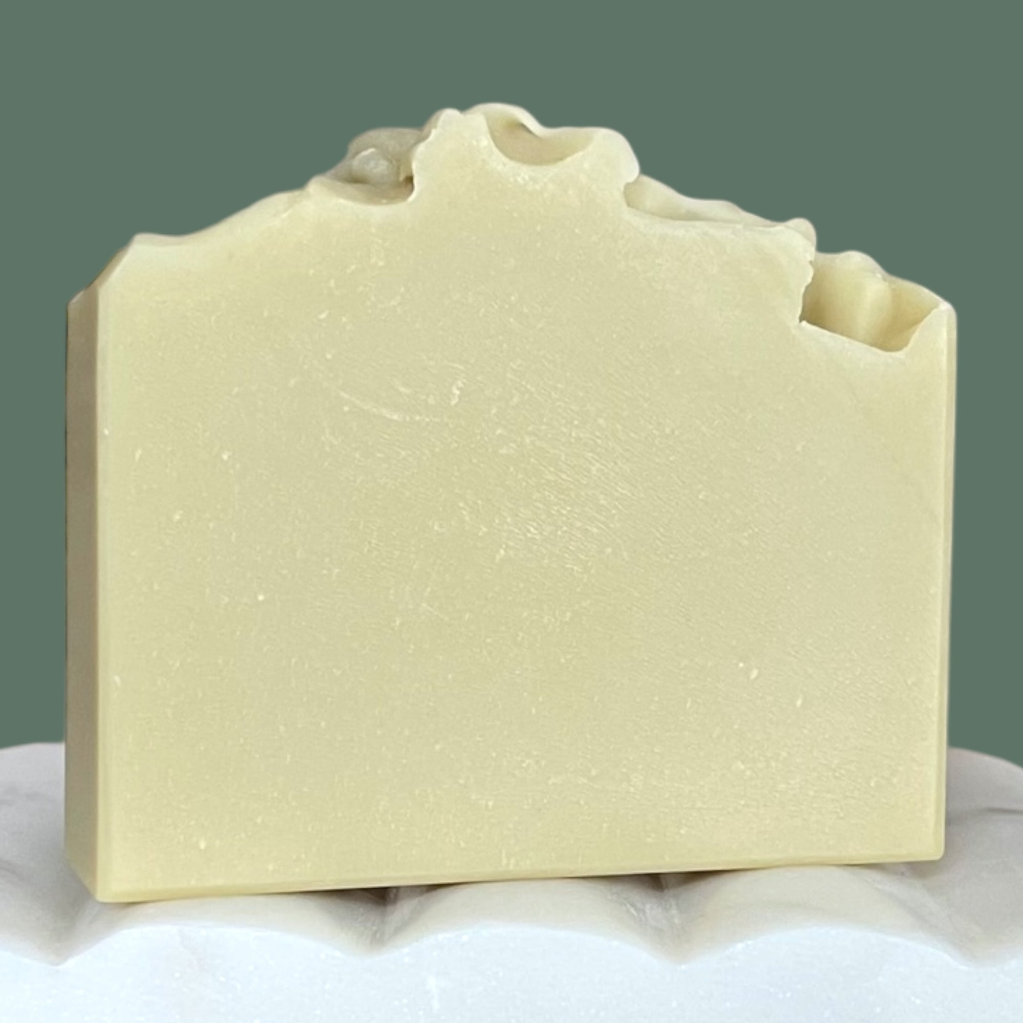 Bar of light green soap on a white surface with a green background
