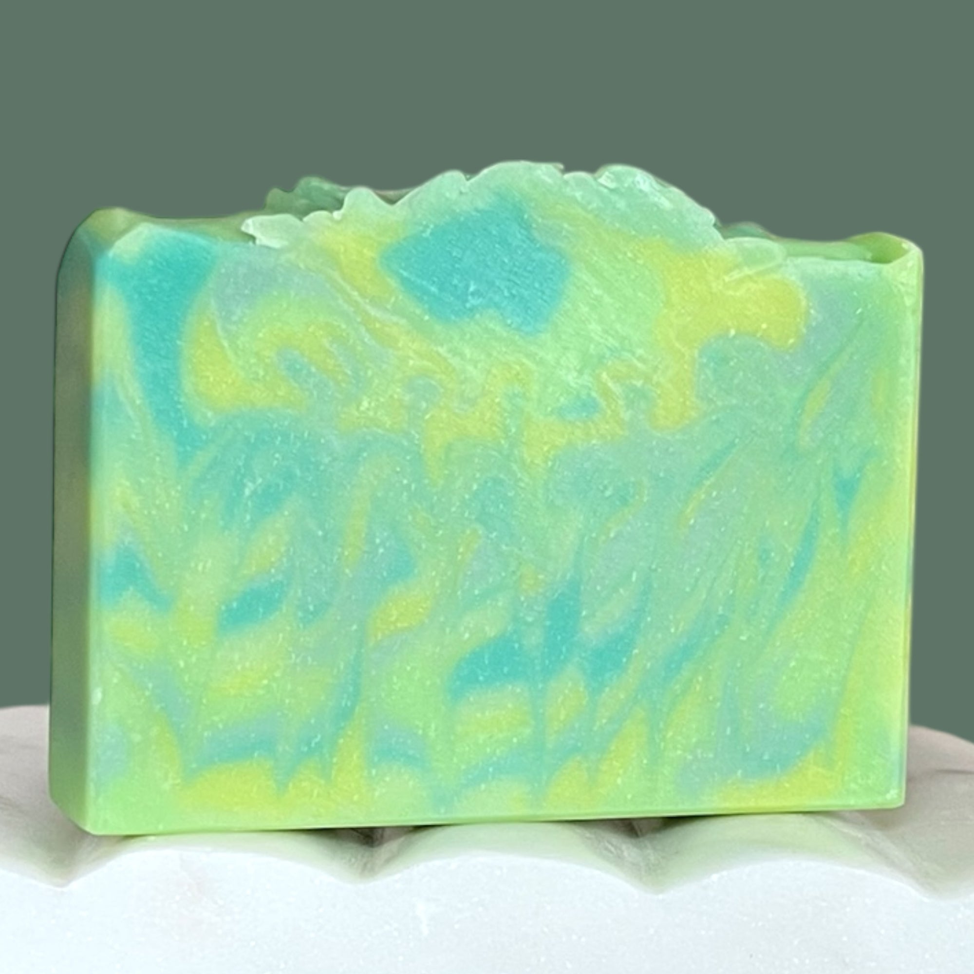 Green marbled soap bar on a white surface with a green background