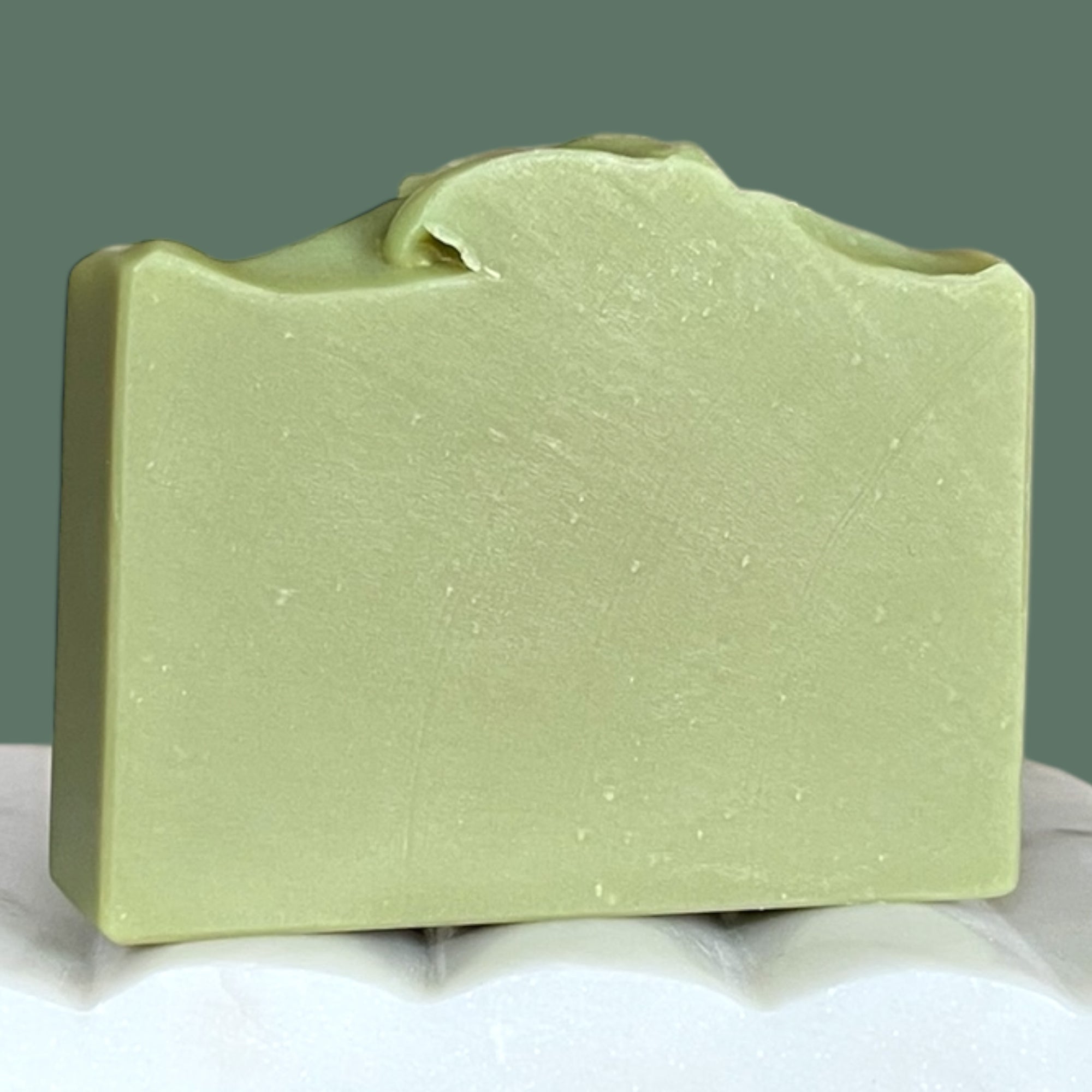 Green bar of soap on a white surface with a green background