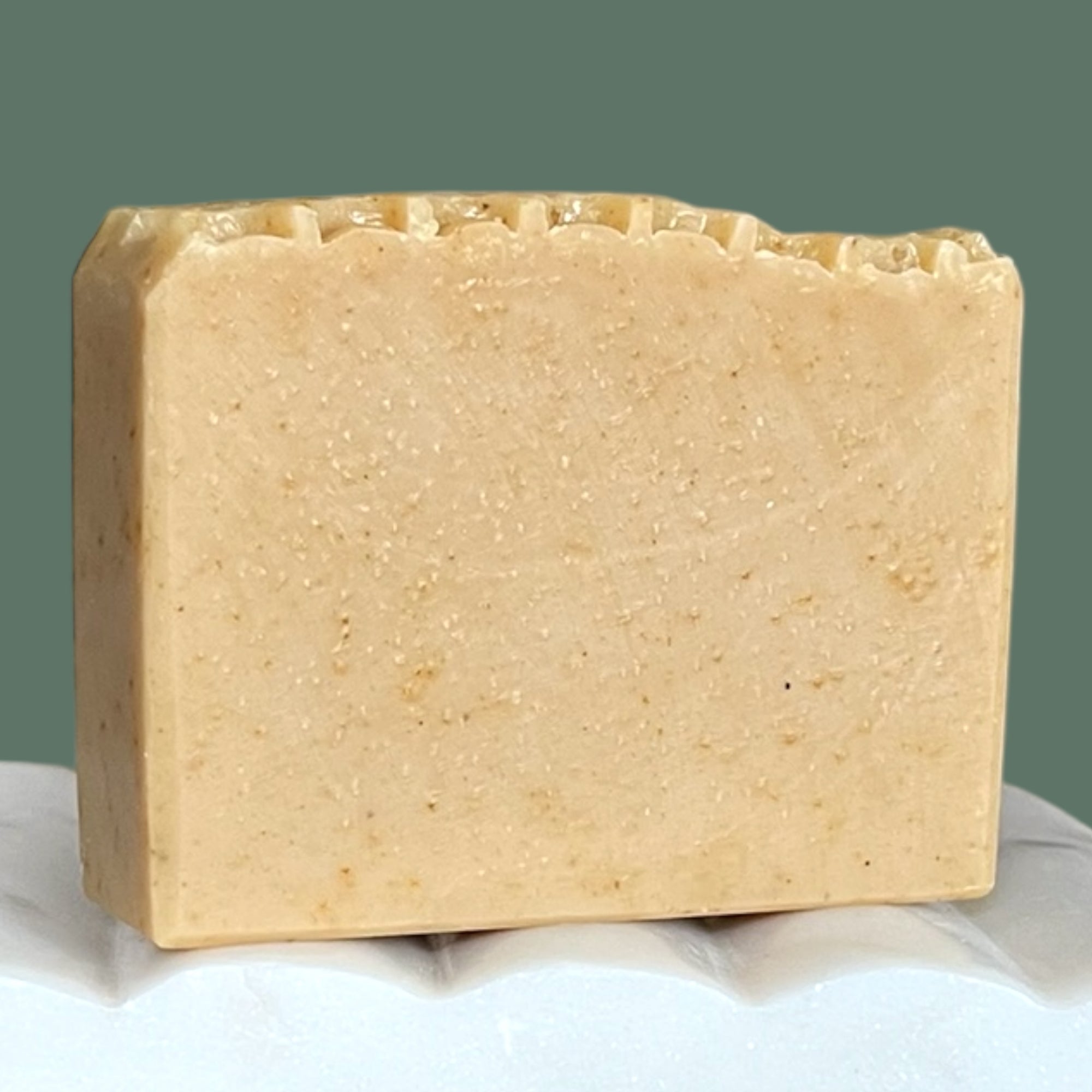Bar of beige soap with a honeycomb textured top with a green background