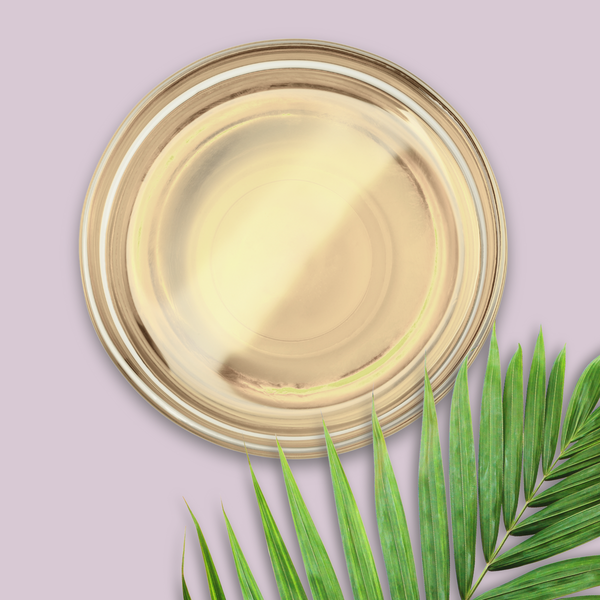 Glass dish of palm oil with green leaves on a light purple background
