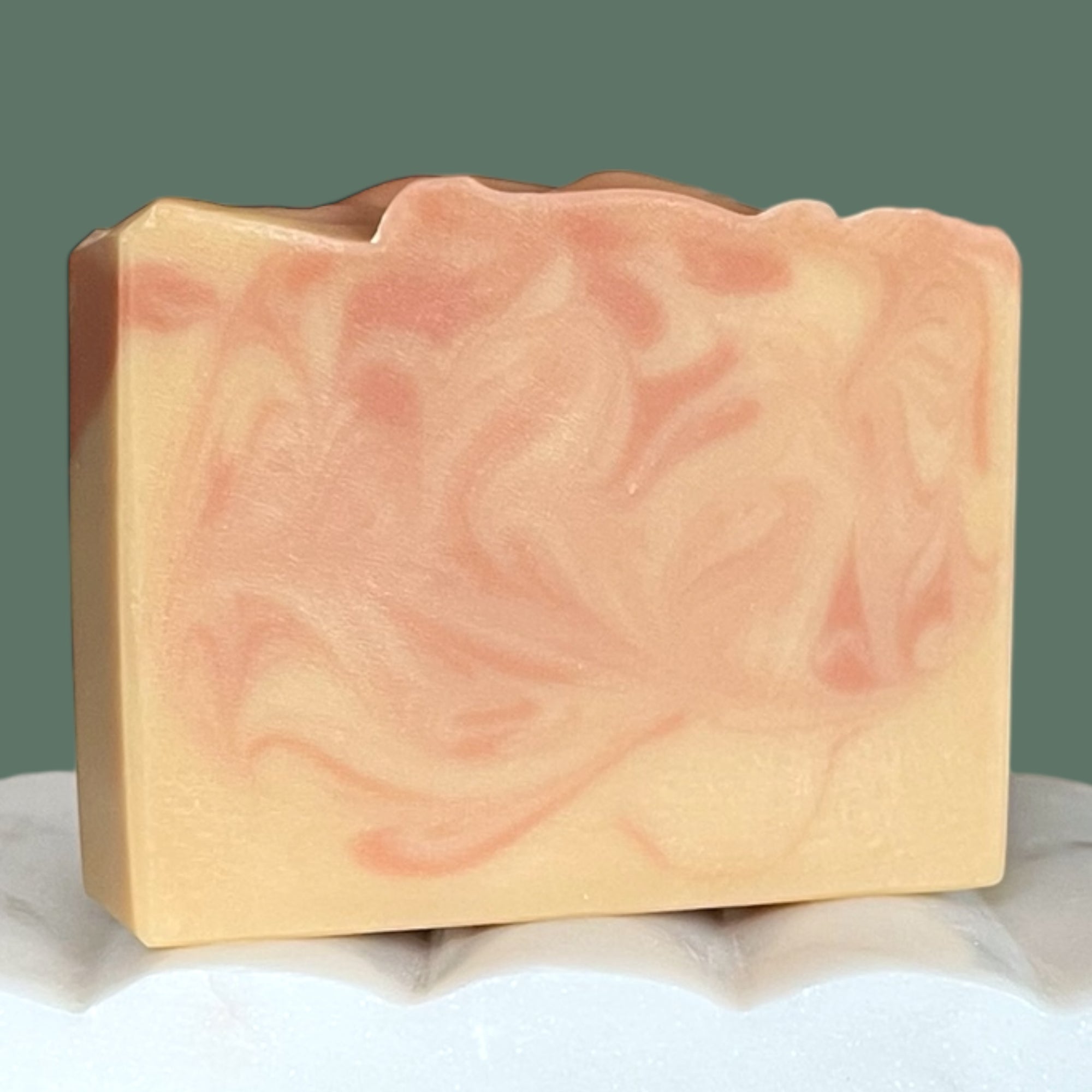 Bar of soap with a marbled pink and beige pattern on a white surface.