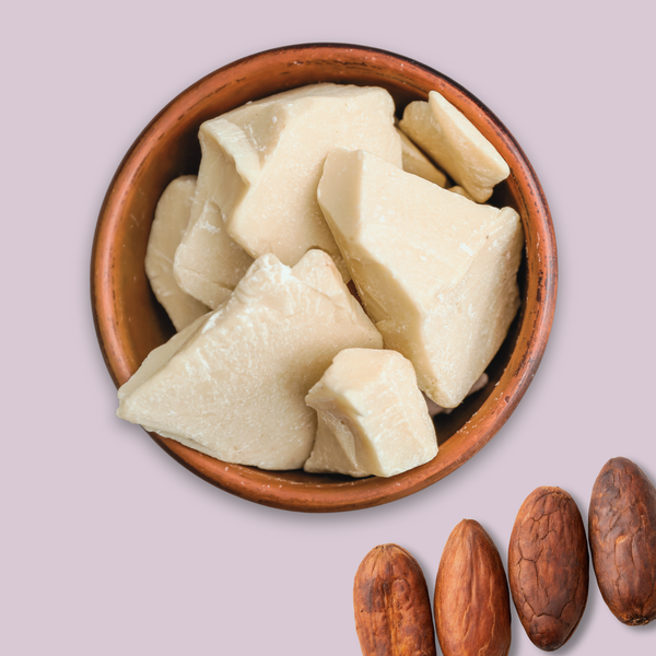 Cocoa butter in a wooden bowl on a light pink background