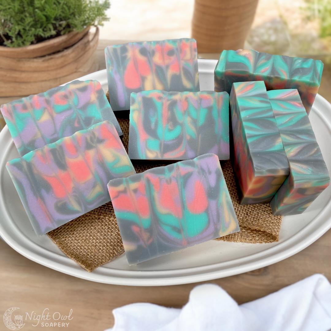 Colorful soap bars on burlap in a white plate with a blurred outdoor background