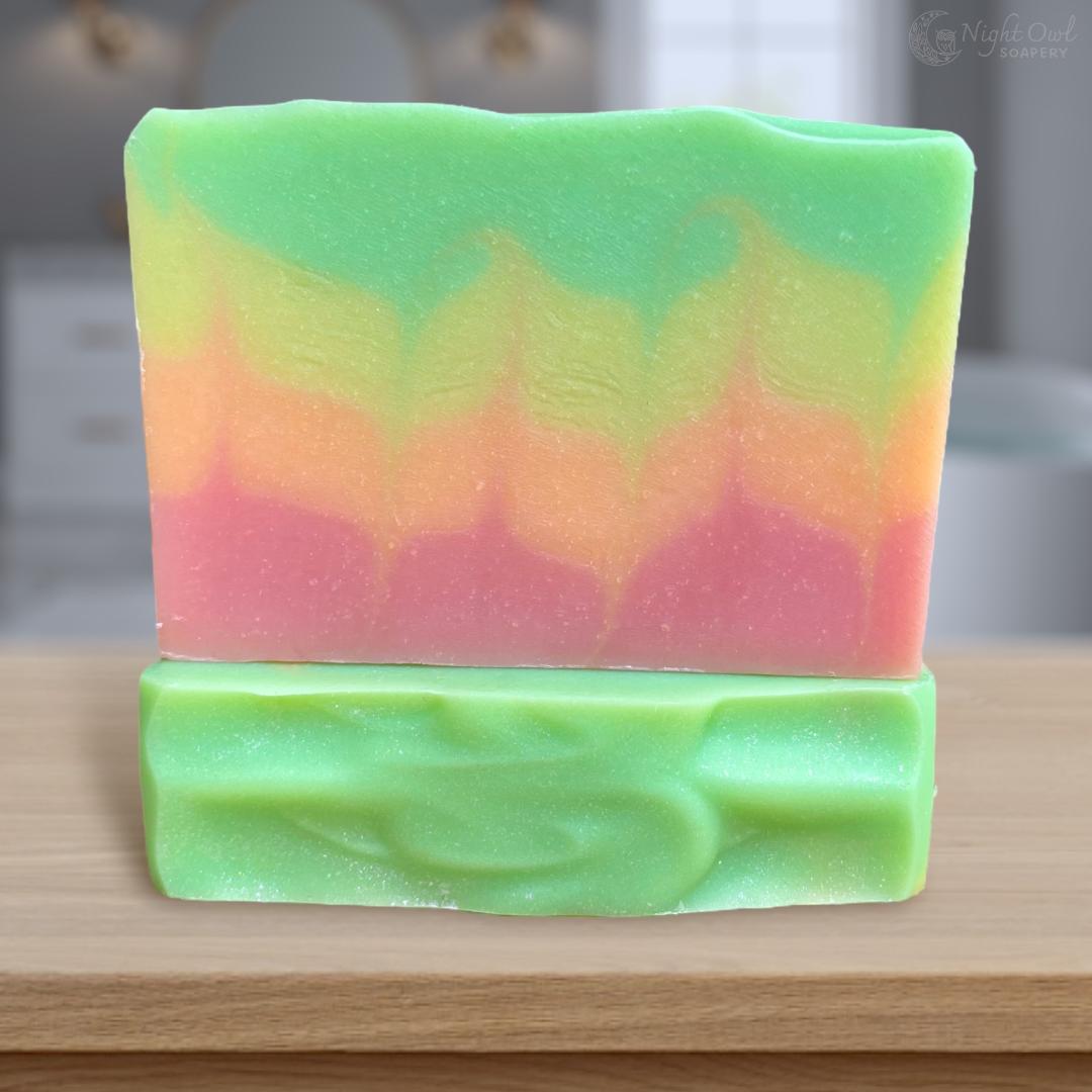 Colorful soap bar with a gradient flame pattern from green to pink on a wooden surface.