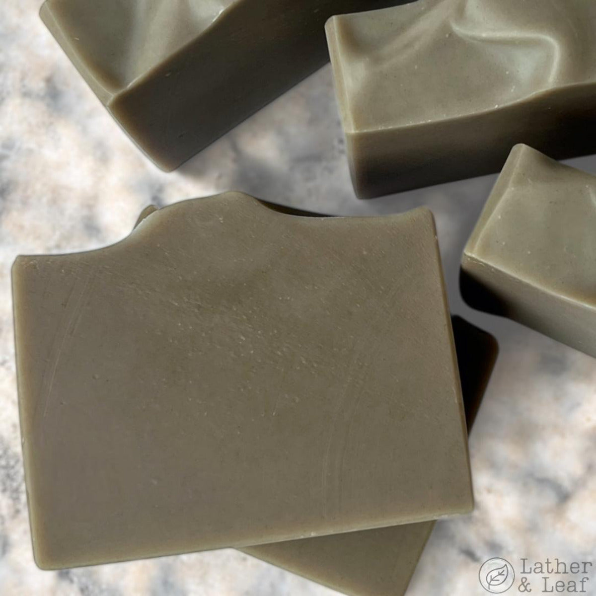Handcrafted bar soap with a gray color, displayed on a marble surface.