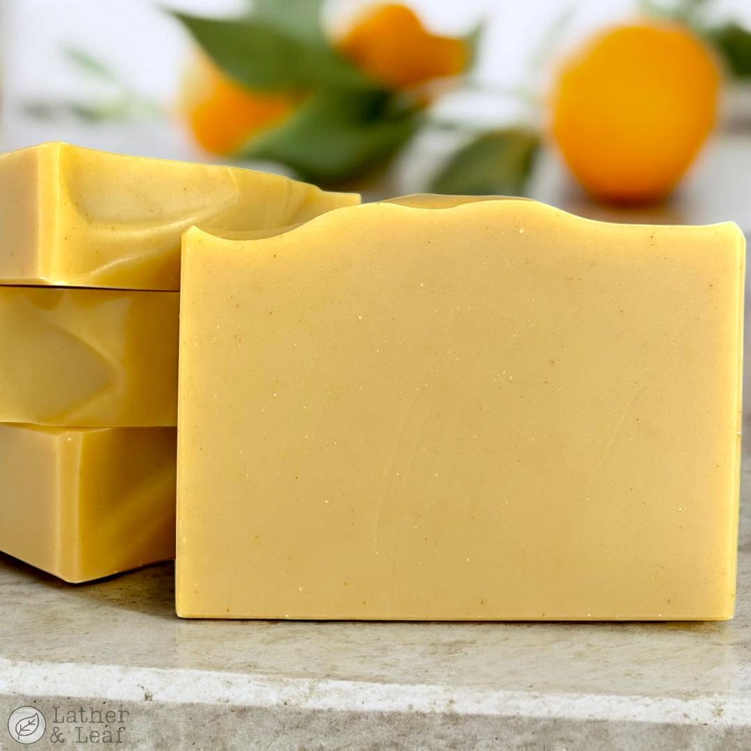 bright orange soap bars on a stone surface with blurred oranges in the background.